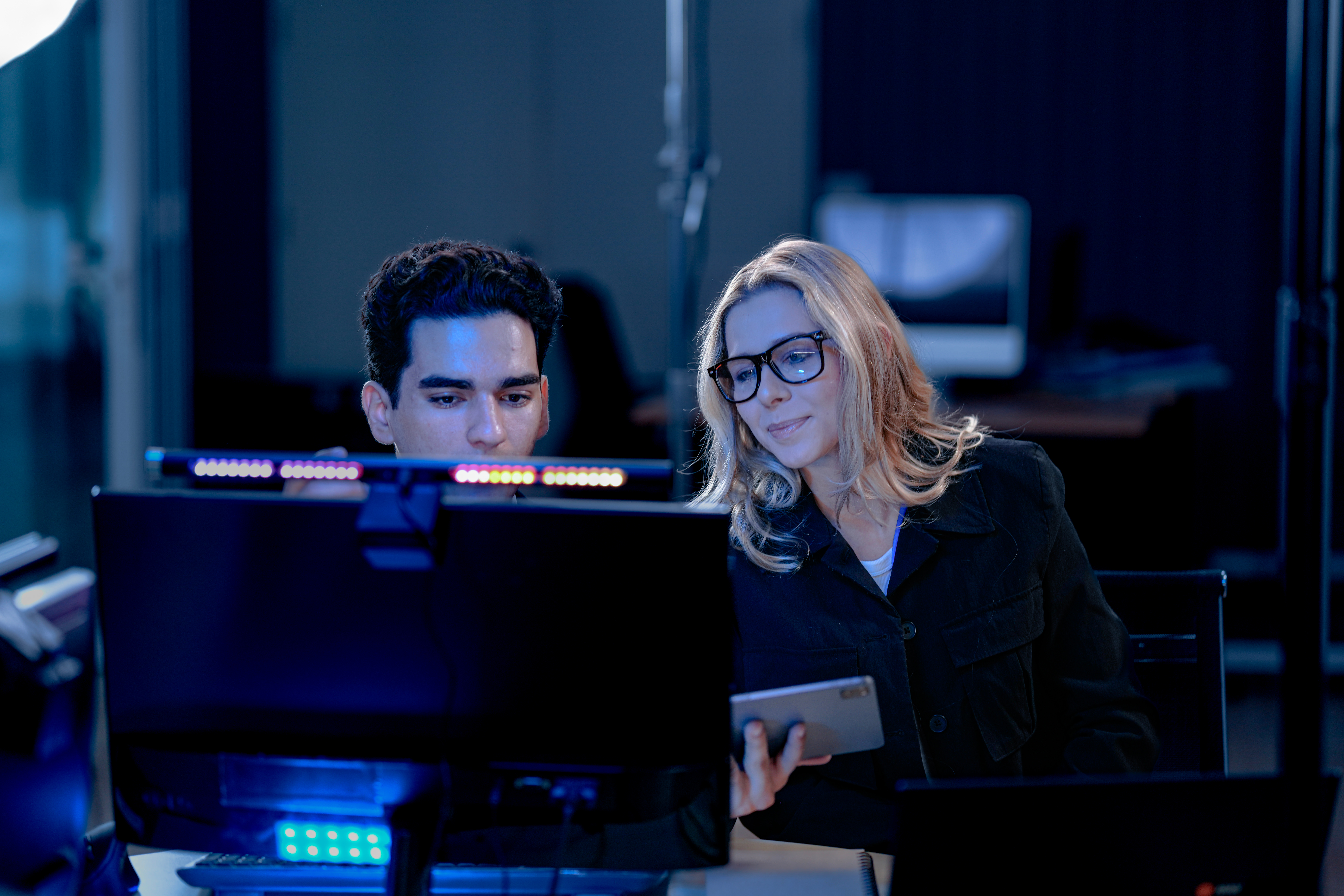 Two professionals reviewing digital project data and analytics on computer monitors.